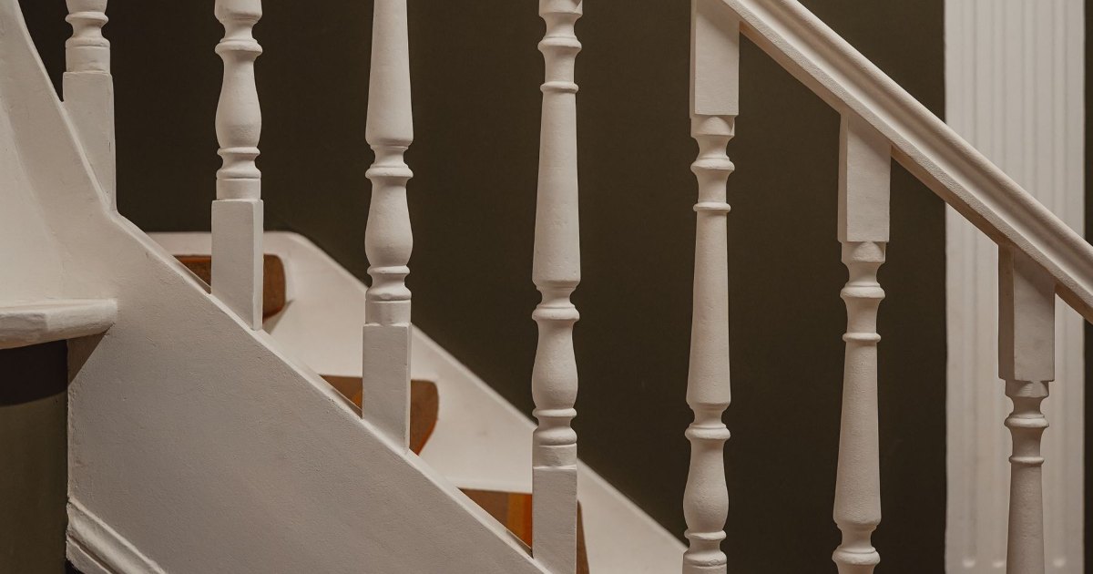 Close view of white painted spindles and a wooden handrail on a staircase