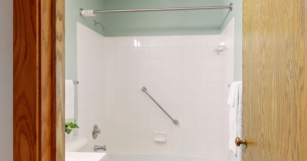 Bath with a wall grab rail A cream bathroom with a bath and a grab rail fitted to the wall