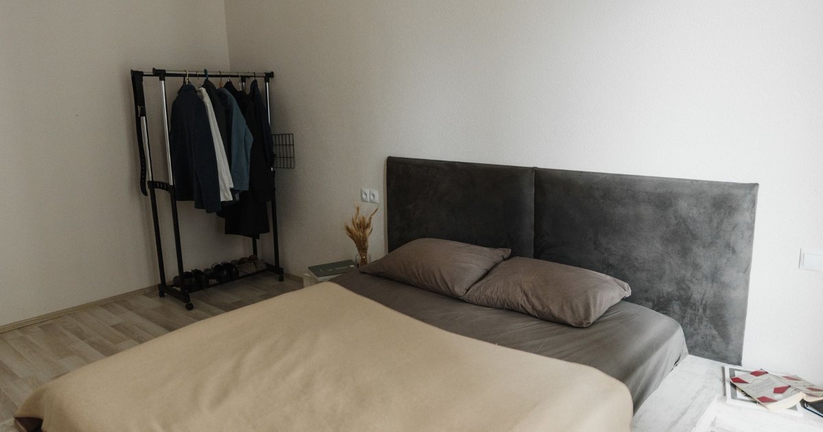 Bed in a minimal bedroom A low bed with dark bedding in a minimal bedroom