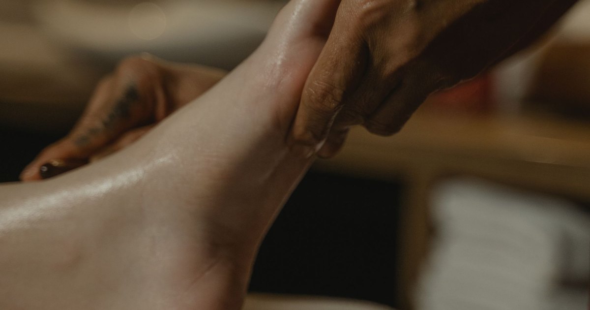 A close view of hands working across the sole of a foot