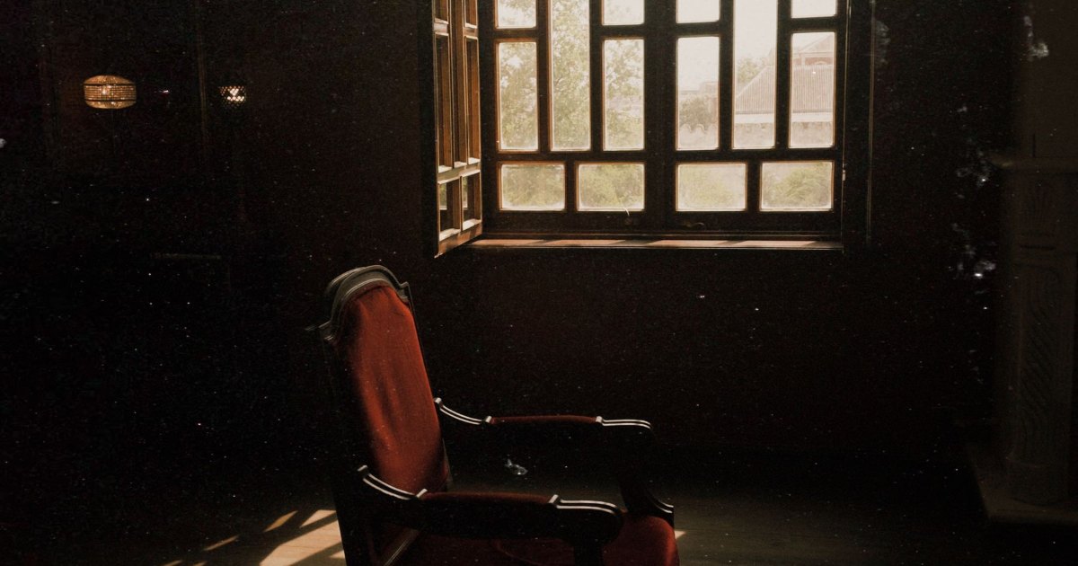Wooden armchair in a corner A dark wooden armchair standing in the corner of a room