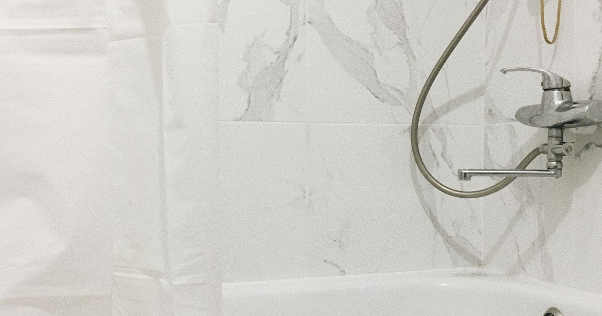 Bath with a shower hose A bath with a hand held shower hose and mixer tap on the wall