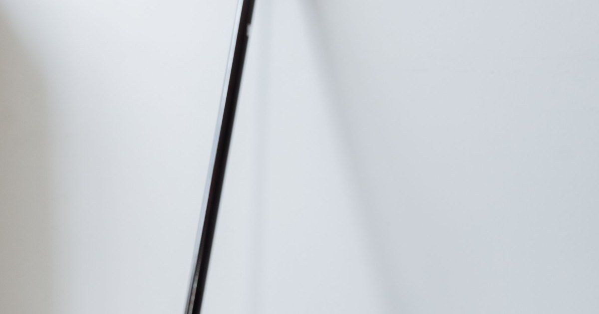 A black walking cane leaning against a plain white wall