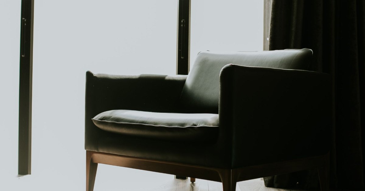 A black upholstered armchair in a simply furnished room