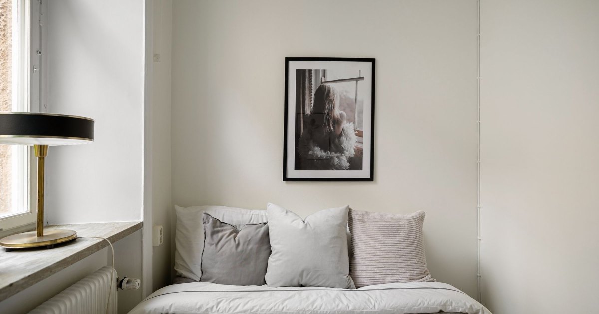 A made bed with a framed picture on the wall above it