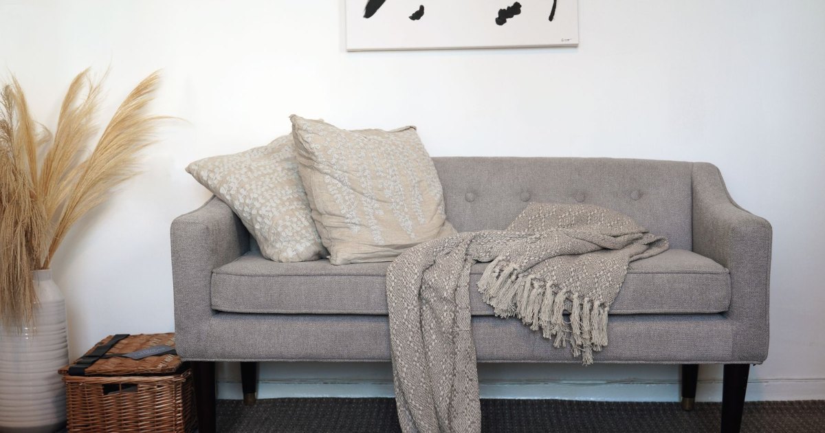 A grey sofa with a folded throw over the arm
