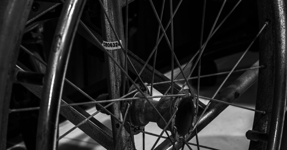 Vintage wheelchair wheel A black and white close view of the metal spokes of an older wheelchair wheel
