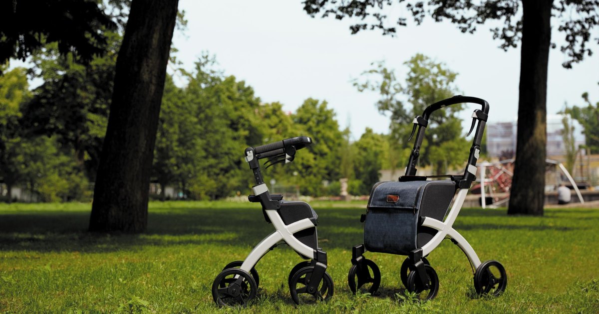 Two rollators outdoors Two four wheeled rollator walkers with seats standing on grass
