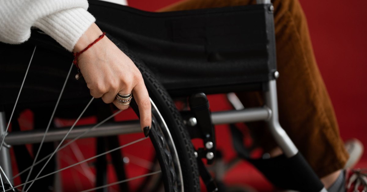 A close view of a hand resting on the armrest of a wheelchair