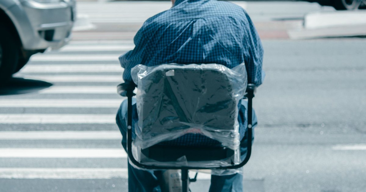 Mobility scooter crossing a road A person riding a mobility scooter across a road crossing, seen from behind