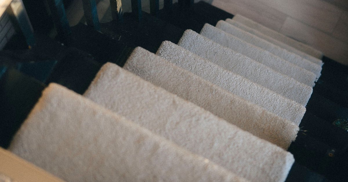 Soft pale carpet running up a plain domestic staircase