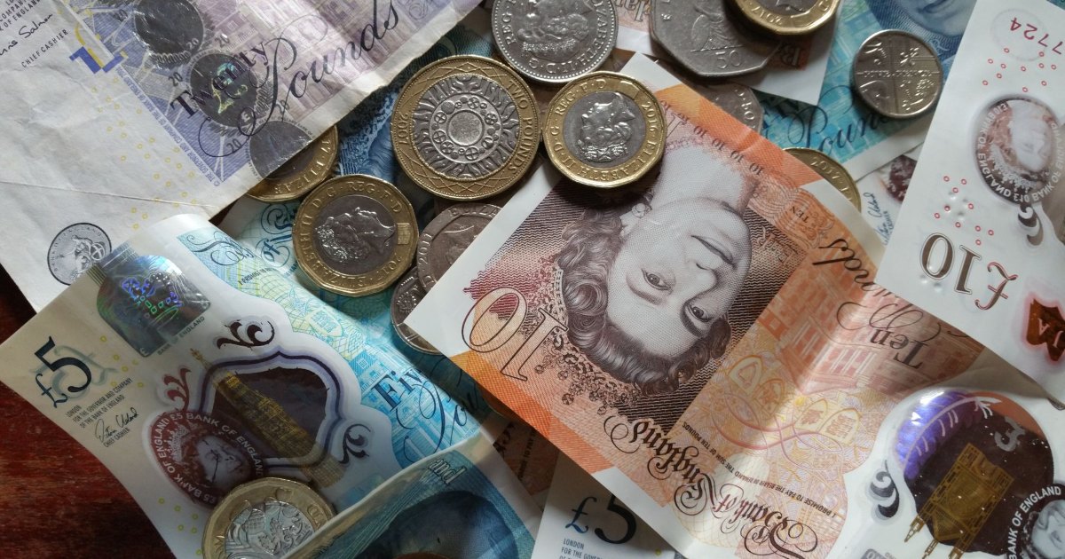 Pound coins and banknotes British pound coins scattered across banknotes