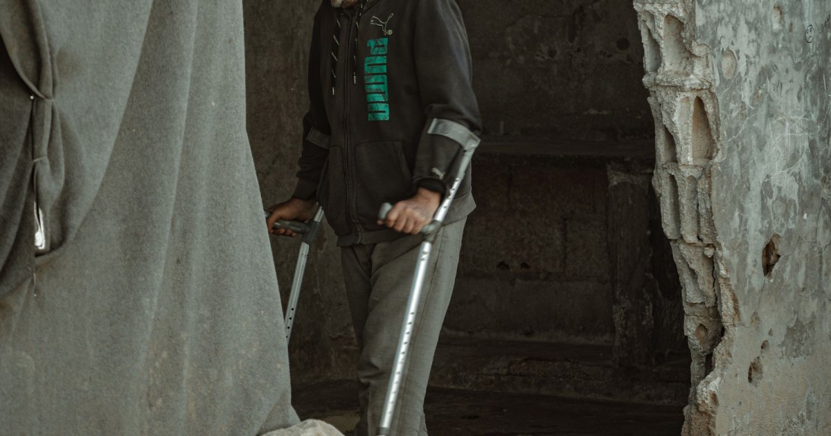 A person using a crutch, photographed from behind