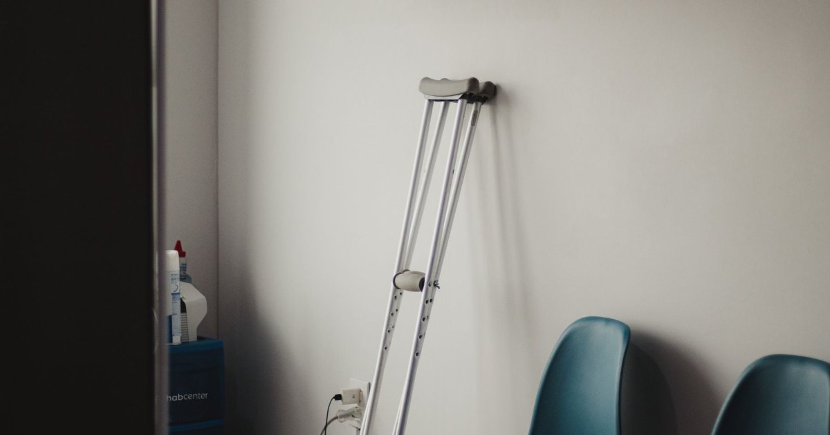 A pair of underarm crutches leaning against a chair in a waiting area