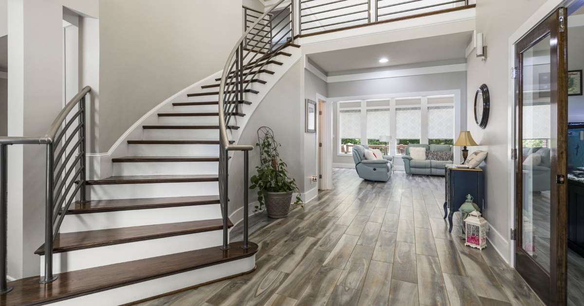 A curved staircase with a stainless steel handrail turning through a modern open plan home, the type of stairs needing a curved stairlift
