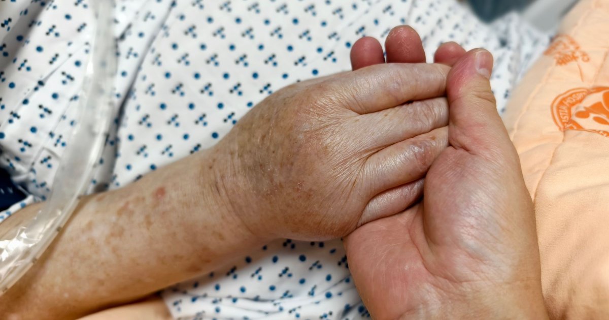 A close view of a hand held gently at a bedside