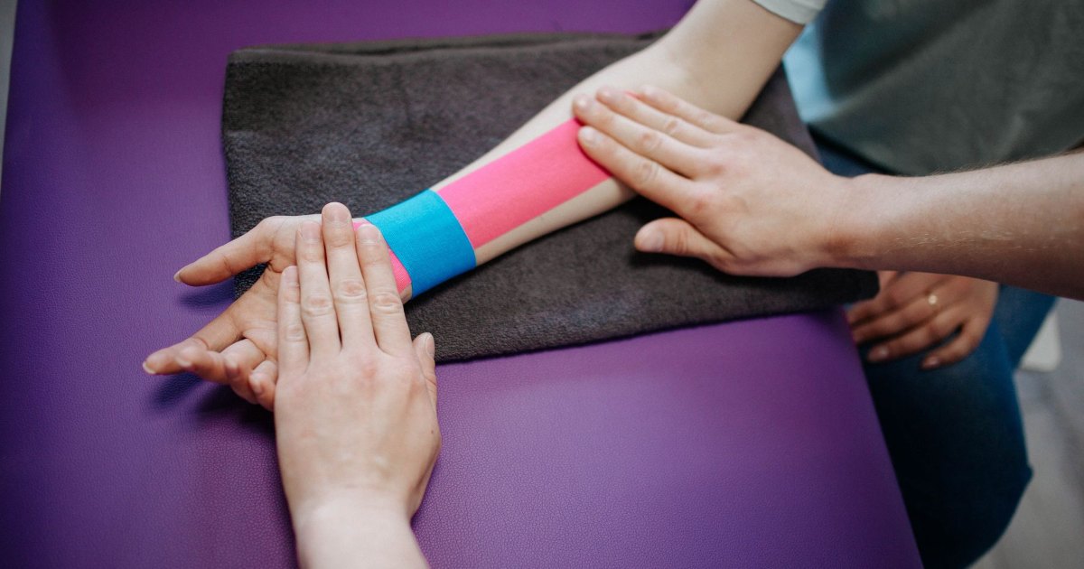 A close view of kinesiology tape being applied to an arm