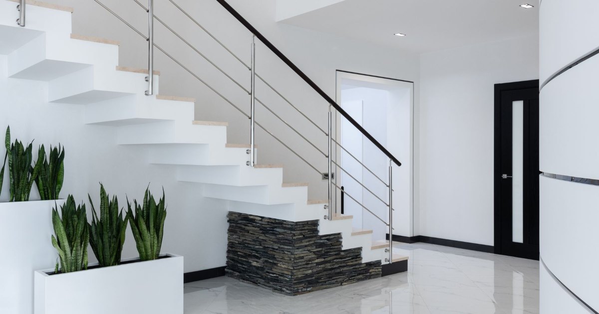 A white open staircase with potted plants at its base