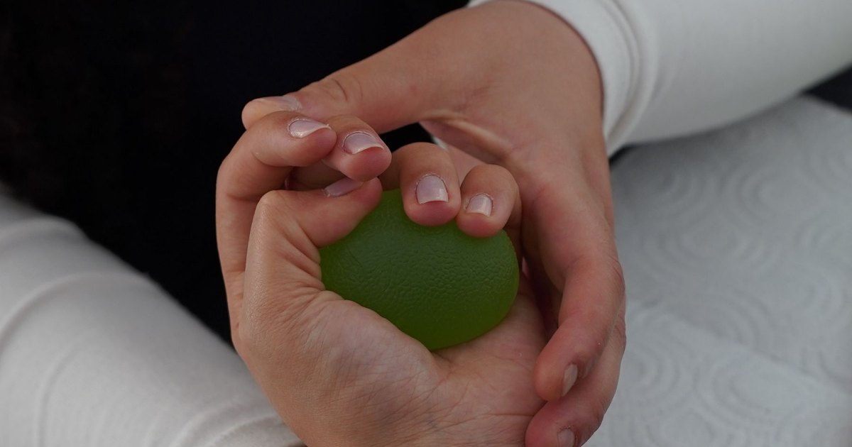 A close view of hands guiding an arm through a stretch