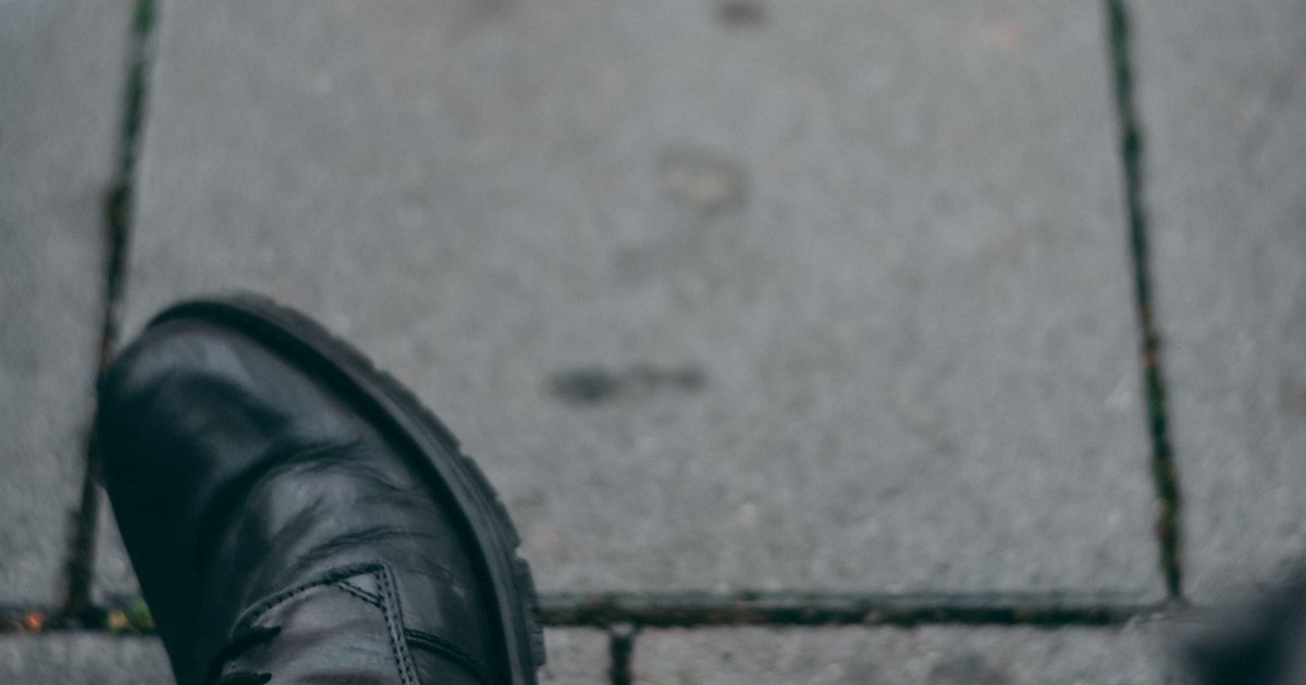 A close view of a shoe stepping on a paved path
