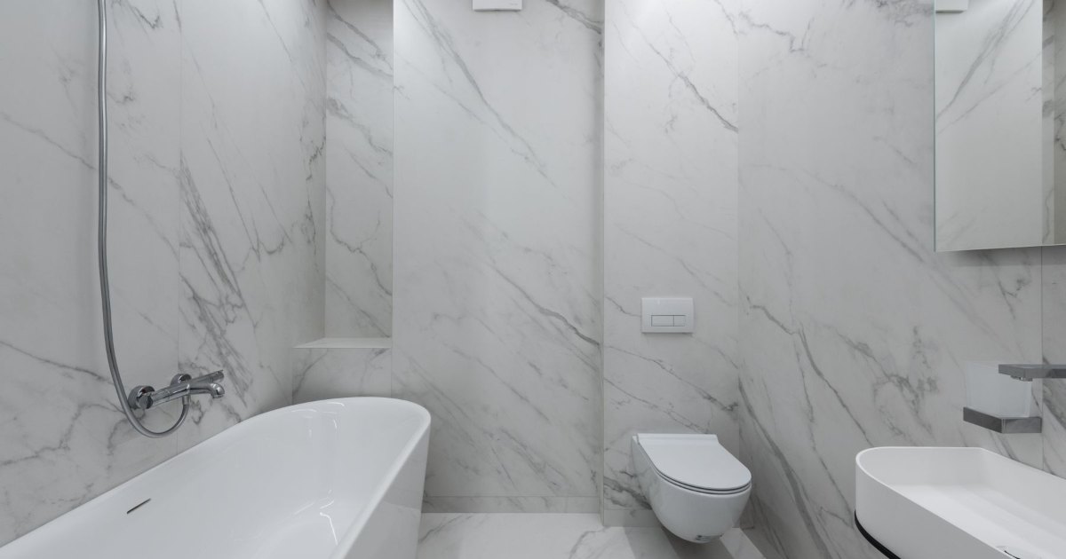 A marble tiled bathroom with a freestanding bath and wall hung toilet