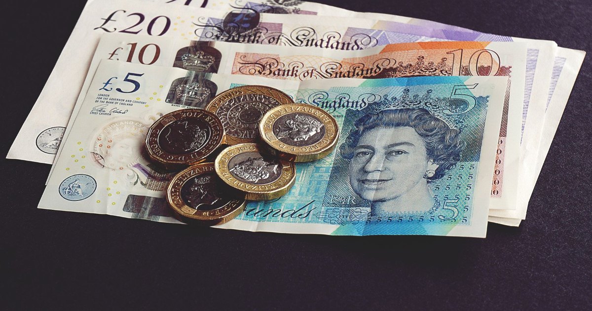 A twenty pound note with British coins resting on it