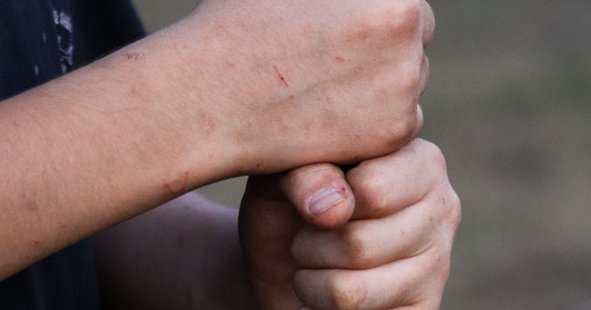A close view of a hand resting on the handle of a walking aid