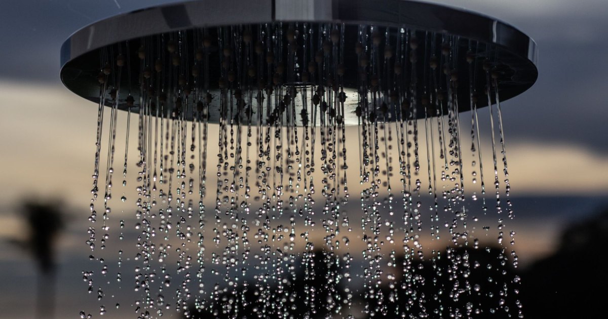 A large round rain shower head with water falling from it