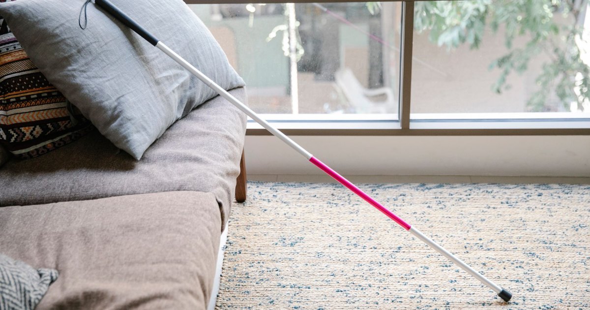 Walking cane on a bed A slim walking cane resting on a bed at home