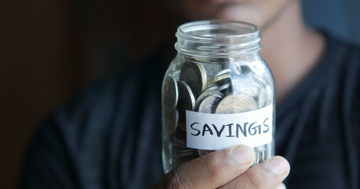 A glass jar labelled savings filled with coins