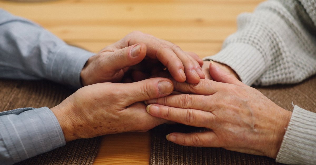 A close view of older hands resting on a table