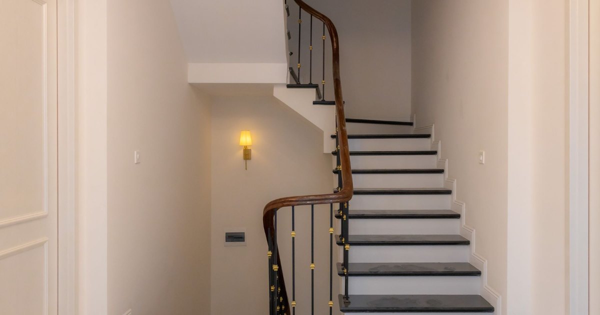 Stairs in a narrow hallway A staircase rising in a narrow, softly lit hallway