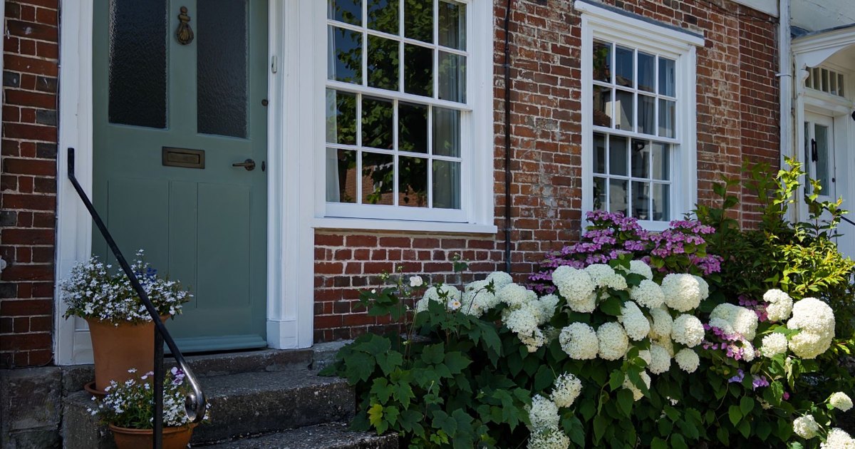 Steps leading to the front door of a red brick British house with hydrangeas beside them, where an outdoor stairlift would be fitted