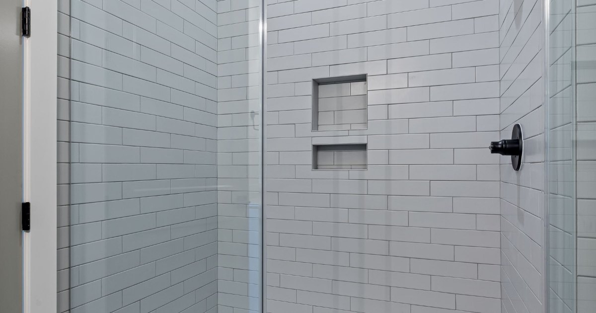 A level access walk-in shower with white metro tiling and a glass screen