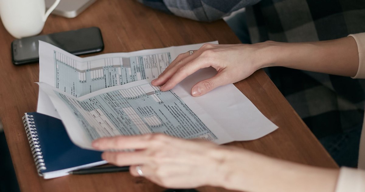 Hands going through printed paperwork on a desk