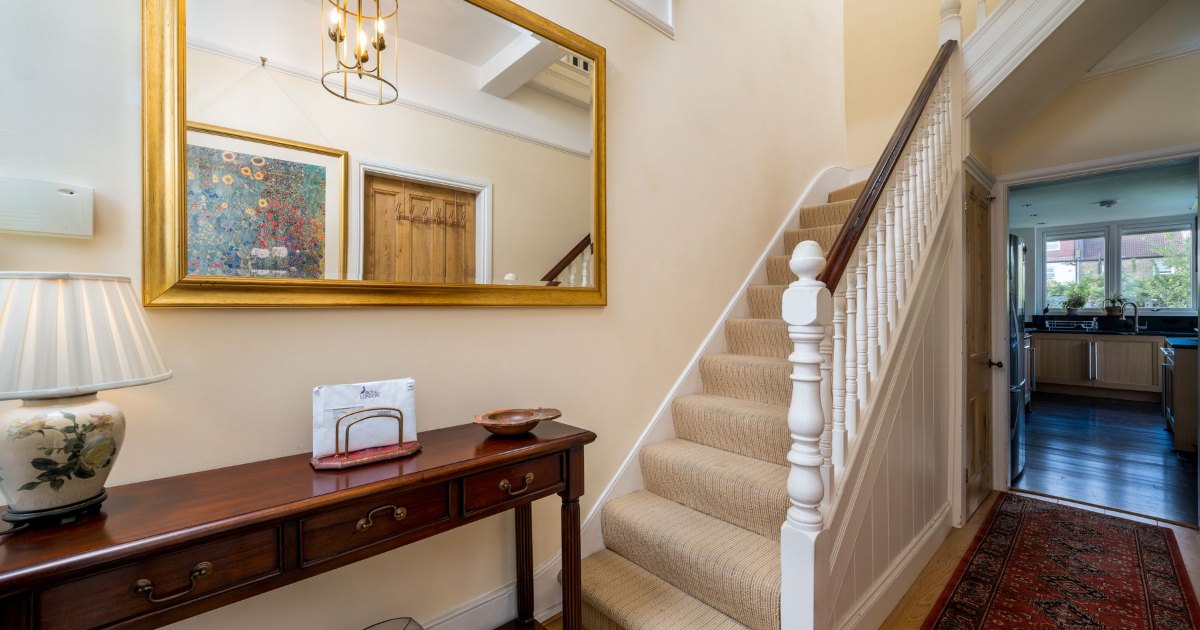 Staircase behind a hall table A staircase rising behind a console table and mirror in a home hallway
