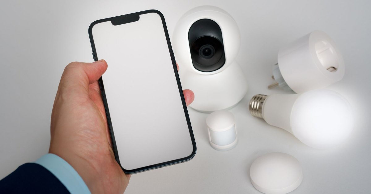 A smartphone showing a smart home control app beside connected home devices