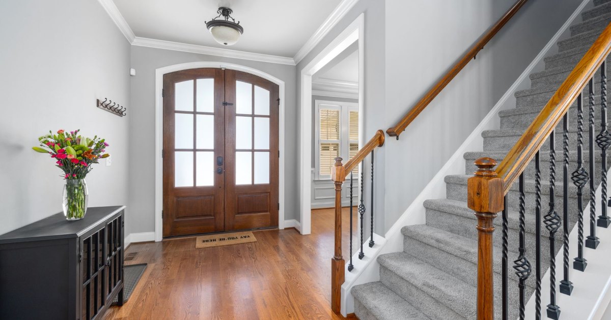 A home hallway with a wooden front door and a carpeted staircase