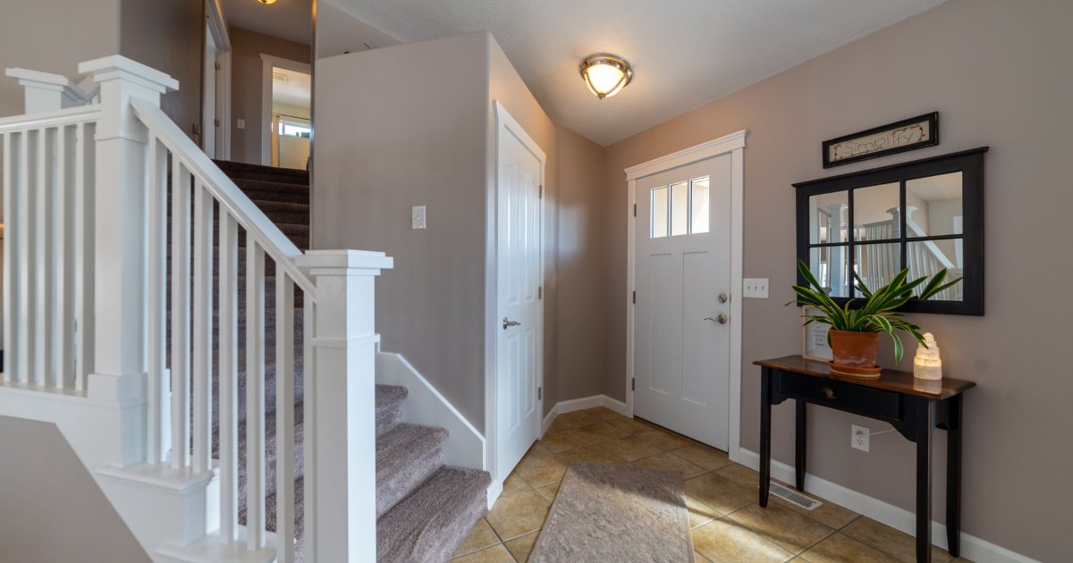 A hallway with a white staircase balustrade and console table
