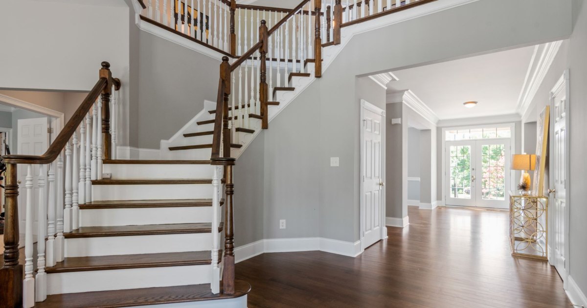 A straight wooden staircase with a white balustrade in a bright home hallway, the type of stairs a straight stairlift is fitted to