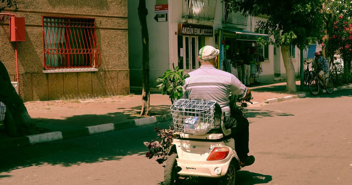 A mobility scooter being ridden along a quiet residential street