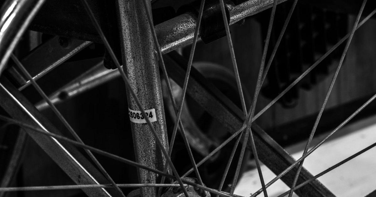 A black and white close view of the spokes of a wheelchair wheel