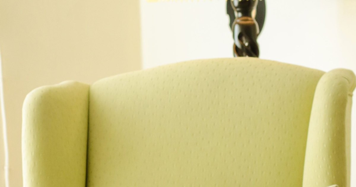 A yellow upholstered armchair in a plain room