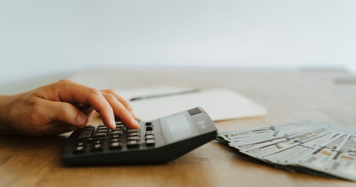 A close view of a hand using a desktop calculator