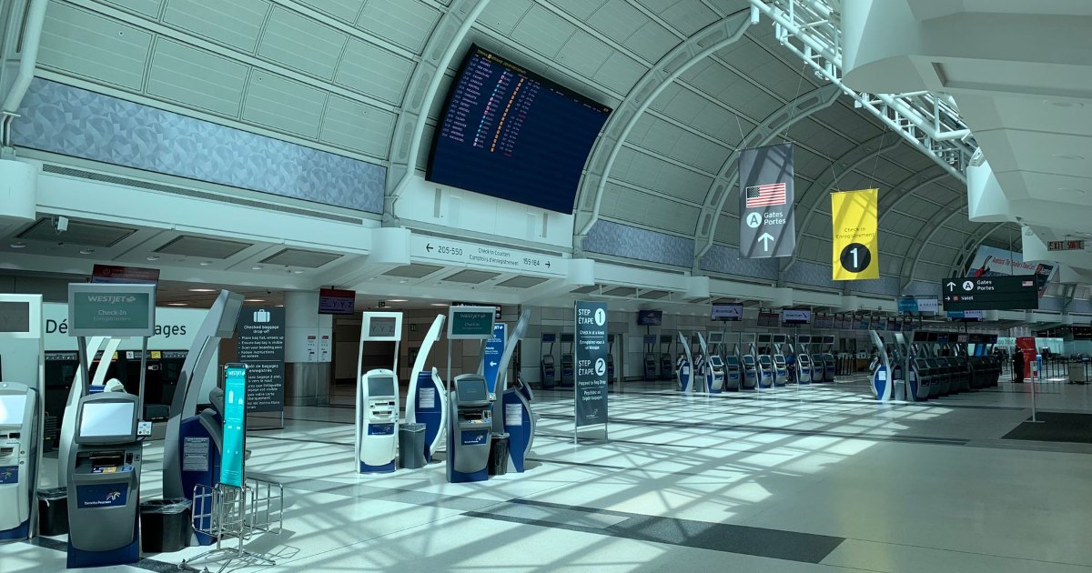 A wide corridor inside a modern airport terminal beneath overhead information signage