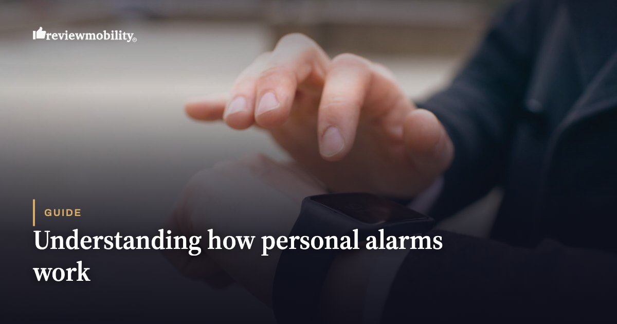 ReviewMobility logo in the top-left; close-up of a person in a suit looking at a smartwatch on their wrist, with the page title 'Guide: Understanding how personal alarms work' overlaid on a dark gradient background.